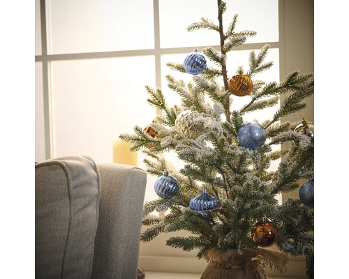 Versierde kleine kerstboom met kerstballen voor een raam