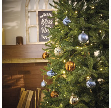 Versierde kerstboom met verschillende kerstballen en een lichtsnoer in de woonkamer.
