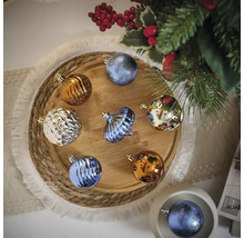 Veelkleurige kerstballen op een houten dienblad naast een kerstboom.