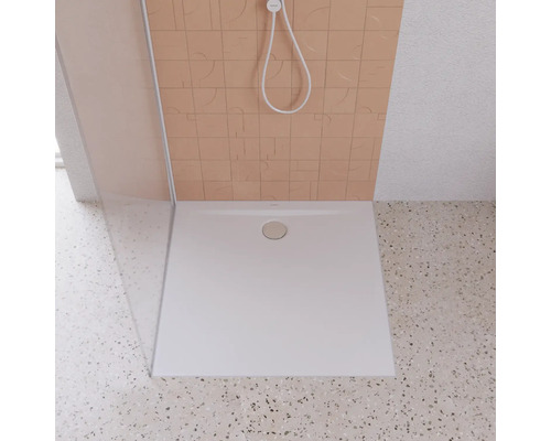 Vierkante douchebak van kunststeen met afvoergarnituur in een douche.