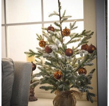 Decoratieve besneeuwde kerstboom met ballen in een jute zak op een vensterbank