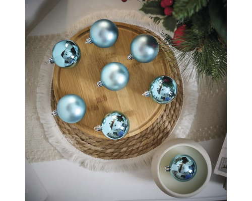 Decoratieve scène met blauwe kerstballen op een houten bord en een gevlochten onderzetter