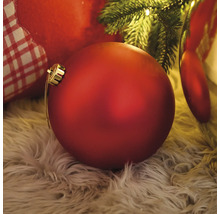 Decoratieve, rode kerstbal op een hoogpolig tapijt