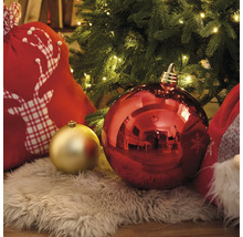 Kerstdecoratie met kerstballen, cadeautas met hertmotief en kunstvachtkleed onder een kerstboom met lichtjes.