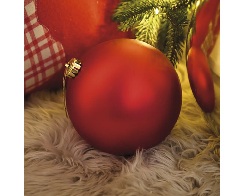 Rode kerstbal op een tapijt onder een kerstboom