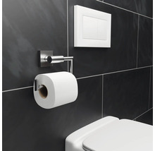 Toilet met toiletpapierhouder, spoelknop en donkere tegelachtergrond