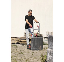 Man vervoert straatstenen met een steekwagen.