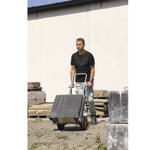 Man vervoert straatstenen met een steekwagen.