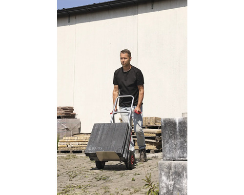 Man vervoert straatstenen met een steekwagen.