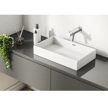 Moderne badkamer met wastafel, kraan, geurstokjes en lotiondispensers op een grijs wastafelmeubel.