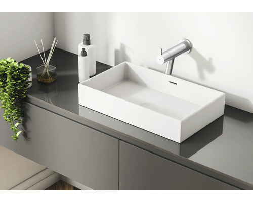 Moderne badkamer met wastafel, kraan, geurstokjes en lotiondispensers op een grijs wastafelmeubel.