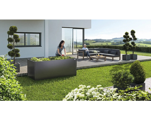 Tuinscène met verhoogde tuinbak, zitgroep en decoratieve plantenbakken op terras en gazon