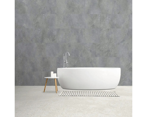 Badkamer met vrijstaand bad, kraan en wandbekleding in betonlook