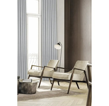 Woonkamer met twee fauteuils, een staande lamp en gordijnen voor een raam