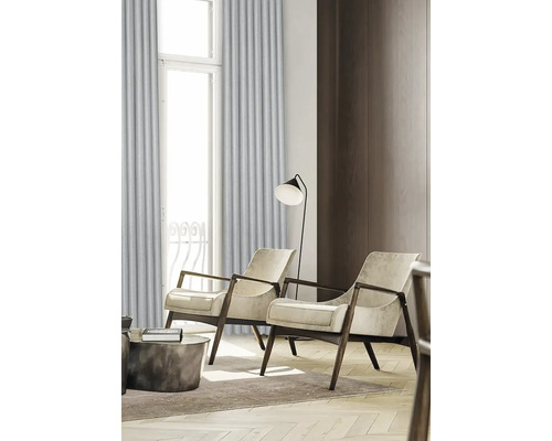 Woonkamer met twee fauteuils, een staande lamp en gordijnen voor een raam