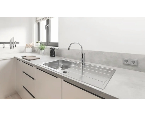 Roestvrijstalen gootsteen met afdruiprek en kraan in een lichte keuken