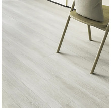 Lichte vinylvloer met houtlook en een stoel met kussen.