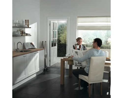 Lichte keuken met vliegengordijndeur, man leest krant aan tafel