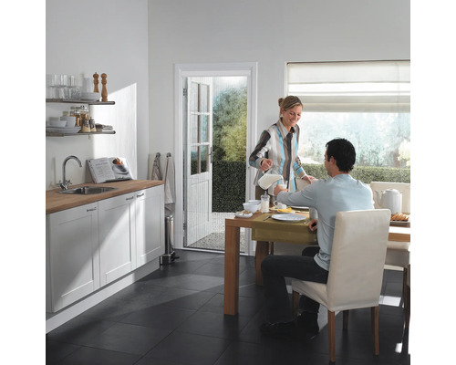 Lichte keuken met eettafel, insectenwerend gordijn bij de deur.