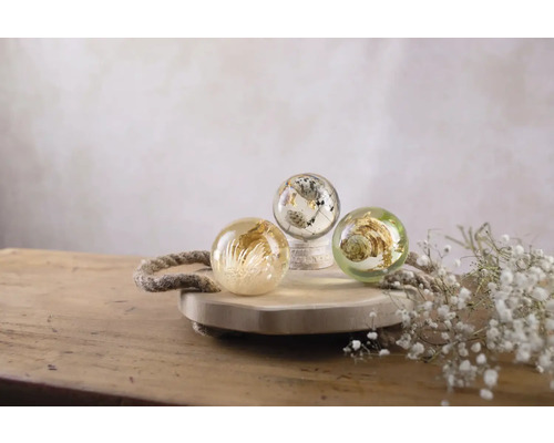 Drie decoratieve bollen met plantenmotieven op een houten dienblad