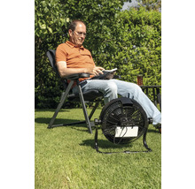 Man leest in de tuin met een draadloze ventilator voor verkoeling