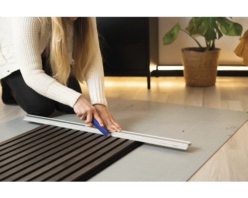 Vrouw snijdt akoestisch paneel met snijgereedschap op snijmat