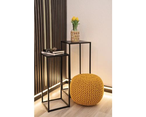 Decoratief interieur met twee bijzettafels, een gebreide poef en een vaas met tulpen