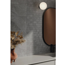 Badkamer met grijze wandtegels in steenlook, spiegel en lamp