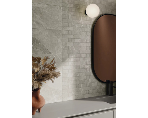 Wanddecoratie met tegels in steenlook en mozaïektegels, gecombineerd met een spiegel en een lamp