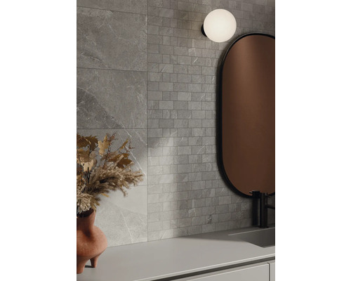 Badkamer met grijze wandtegels in steenlook, spiegel en lamp