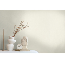 Decoratieve scène met een vaas, takken, een kaars, een klok en een sculptuur op een tafel.