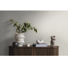Decoratieve elementen op een houten kast met gegroefde structuur: een gedraaide vaas met takken, een kleine bol, een blik, boeken, een hartvorm en een vrouwelijke torsosculptuur.