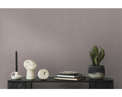 Close-up van een behang met motief met een tafel met een kaars, beeldhouwwerk, klok, boeken en een potplant.