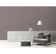 Woonkamer met fauteuil, lamp en decoratieartikelen op dressoir voor een wand met patroon