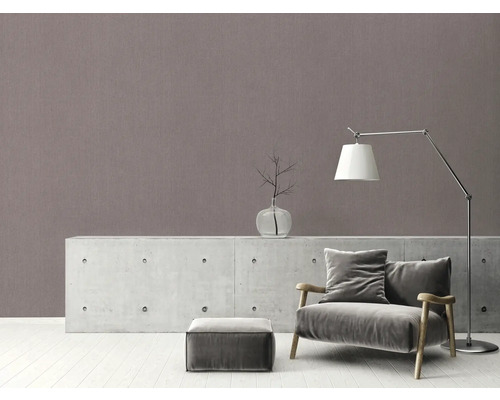 Woonkamer met fauteuil, lamp en decoratieartikelen op dressoir voor een wand met patroon