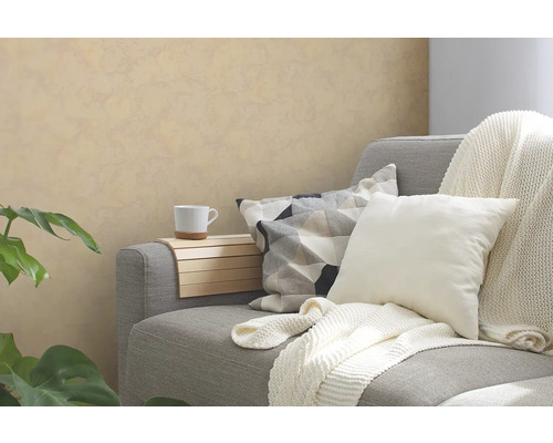 Grijze bank met kussens, deken, armleuningblad en beker in een woonkamer.