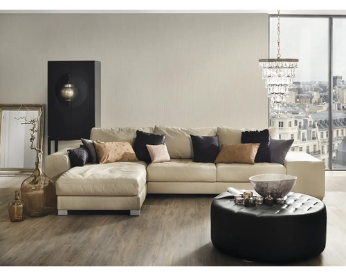 Woonkamer met hoekbank, poef, salontafel en decoraties.