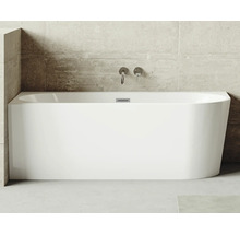 Rechthoekig bad van sanitairacryl met armaturen tegen een betonnen muur