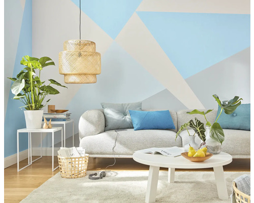 Woonkamer met bank, tafel, lamp en kamerplanten voor een wand met geometrische patronen