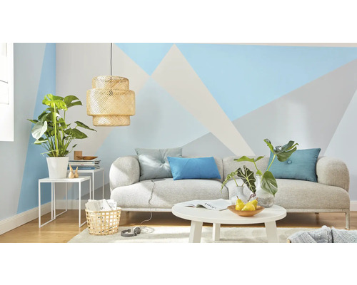 Woonkamer met bank, tafel, lamp en kamerplanten voor een muur met geometrische patronen