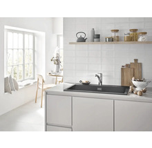 Lichte keuken met spoelbak, kraan en keukengerei op het aanrecht.