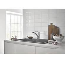 Moderne keuken met spoelbak, kraan en keukengerei op een helder aanrecht.