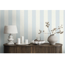 Decoratieve kamer met gestreept behang, tafellamp, kaarsen, schaal en vaas op een kast