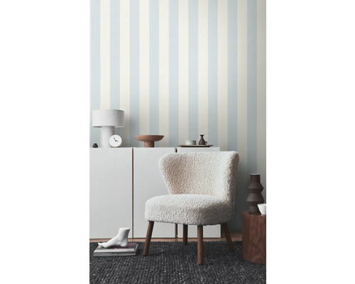 Woonkamer met gestreept behang en een fauteuil met houten poten