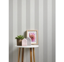 Decoratief interieur met gestreept behang, tafel, plant, fotolijst en decoratie.