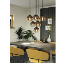 Eetkamer met eettafel, stoelen en een hanglamp met meerdere glazen bollen.