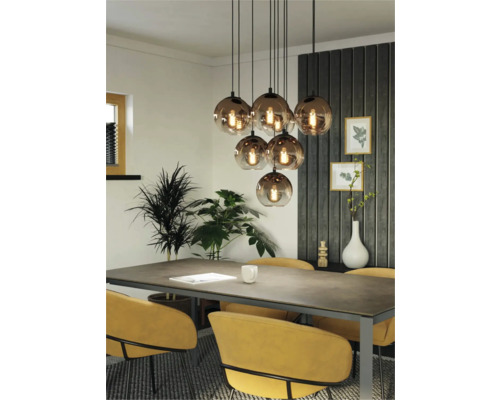 Eetkamer met eettafel, stoelen en een hanglamp met meerdere glazen bollen.