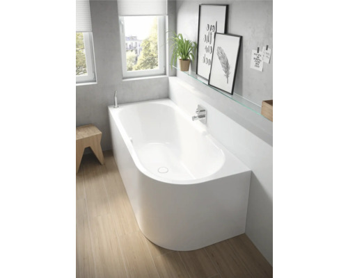 Badkamer met wit ligbad en houten vloer