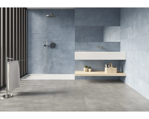 Lichte badkamer met douche, wastafel en grijze vloertegels.