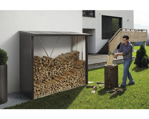 Houtopslag met brandhout en man die hout hakt in de tuin.